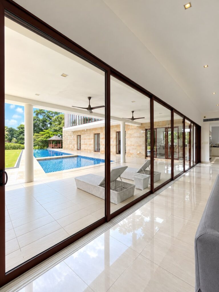 Large-scale aluminium sliding door overlooking a landscaped courtyard, featuring a 10,400mm wide six-panel glass door system by CT Aluminium.