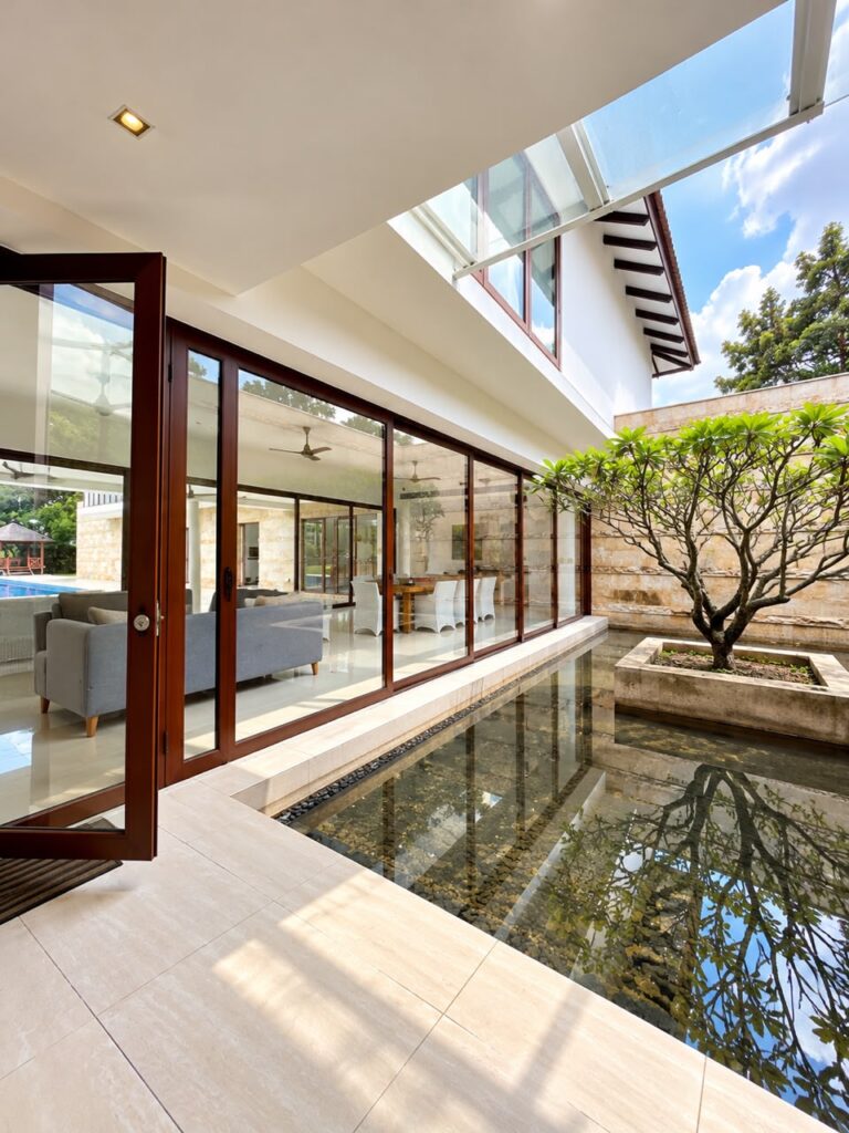 Large-scale aluminium sliding door overlooking a landscaped courtyard, featuring a 10,400mm wide six-panel glass door system by CT Aluminium.