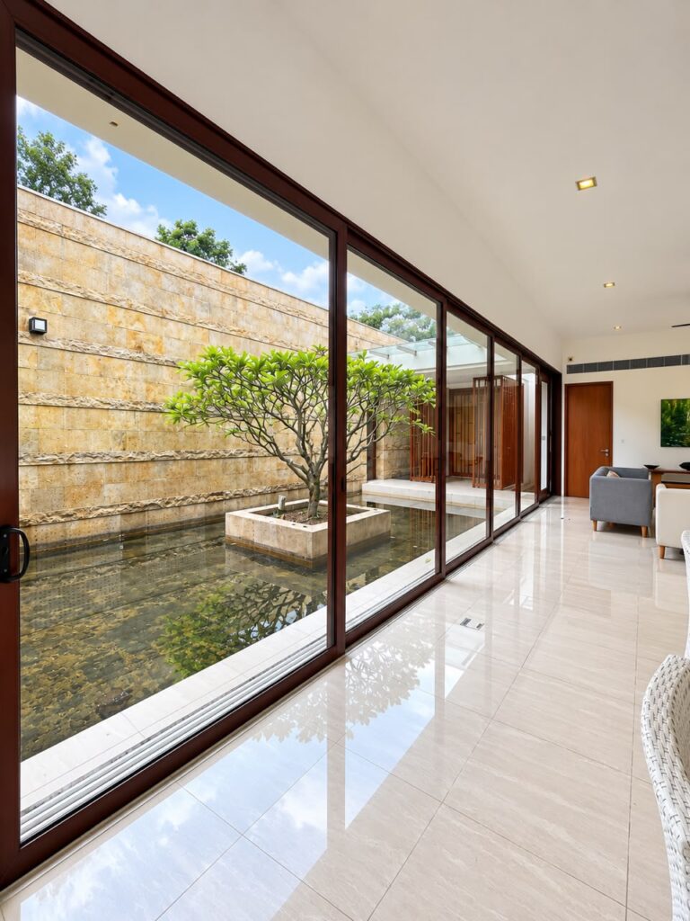 Large-scale aluminium sliding door overlooking a landscaped courtyard, featuring a 10,400mm wide six-panel glass door system by CT Aluminium.